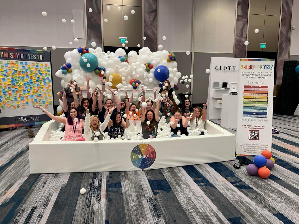 Clubbies throwing balls in the air in a ball pit at a MäksēLife event