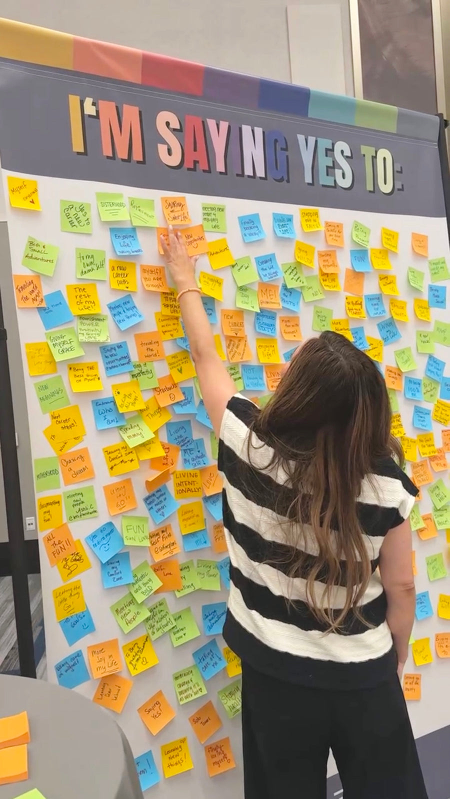Sierra placing a note on the Saying Yes wall at a MäksēLife event